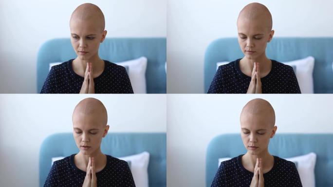 忠实的年轻肿瘤中心秃头女性患者在室内祈祷。
