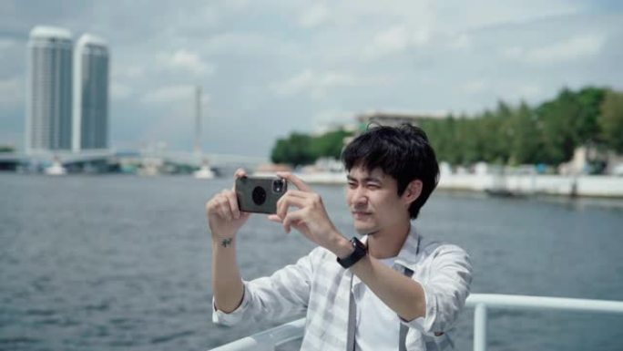 年轻的亚洲男子站在河边拍照。