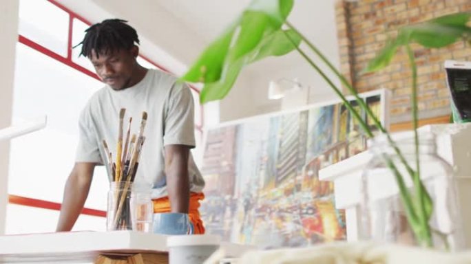 非裔美国男性画家在艺术家工作室里拿着画笔思考