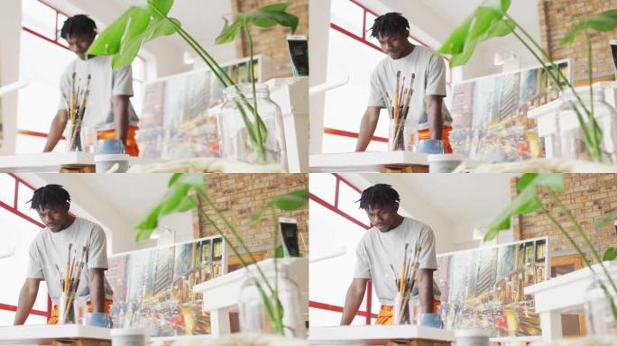 非裔美国男性画家在艺术家工作室里拿着画笔思考