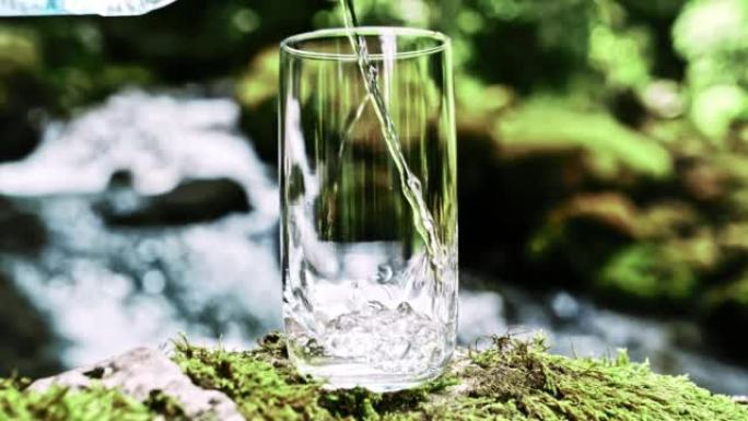 超级SLO MO将新鲜的矿泉水倒入河边的玻璃杯中