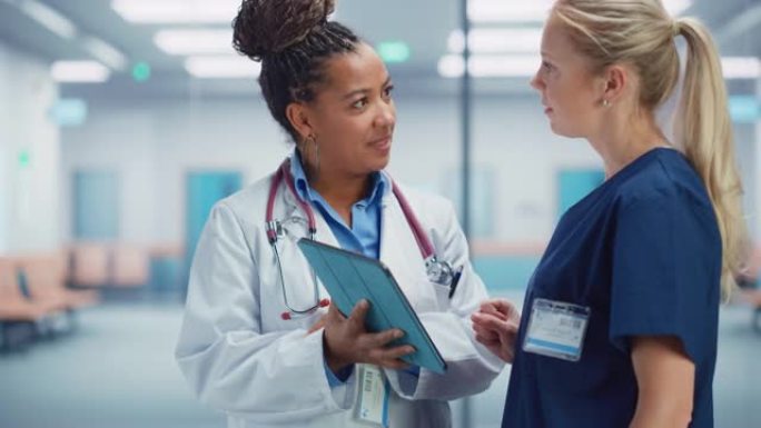 医疗医院: 专业黑人女医生使用数字平板电脑与白人女护士交谈。两名医疗保健专家讨论，寻找挽救生命的治疗