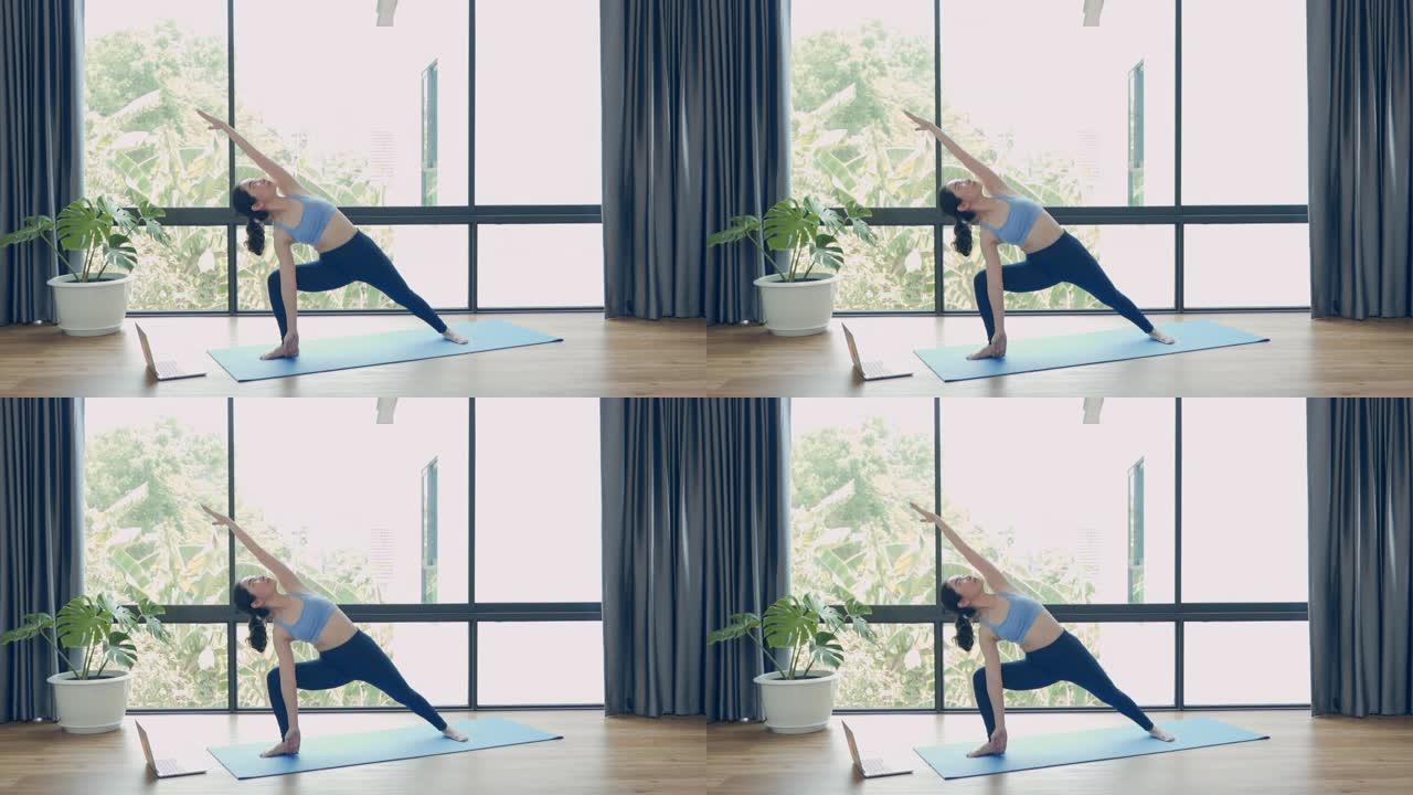 亚洲女子在家用笔记本电脑练习瑜伽