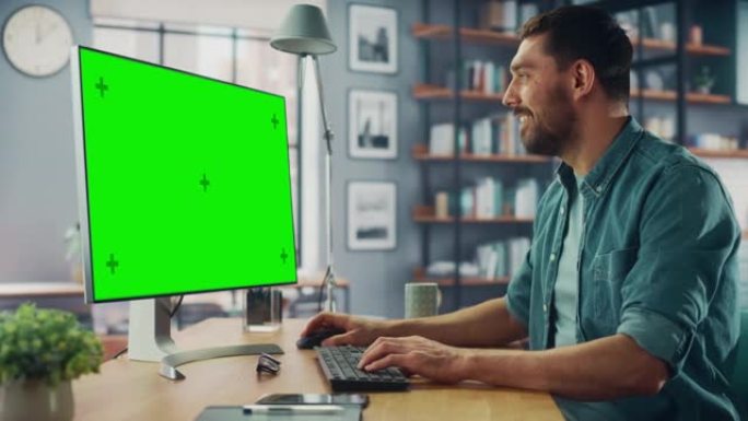 英俊的高加索专家在家用客厅的台式电脑上工作，绿屏模拟显示。自由职业者在社交网络上通过互联网与客户聊天