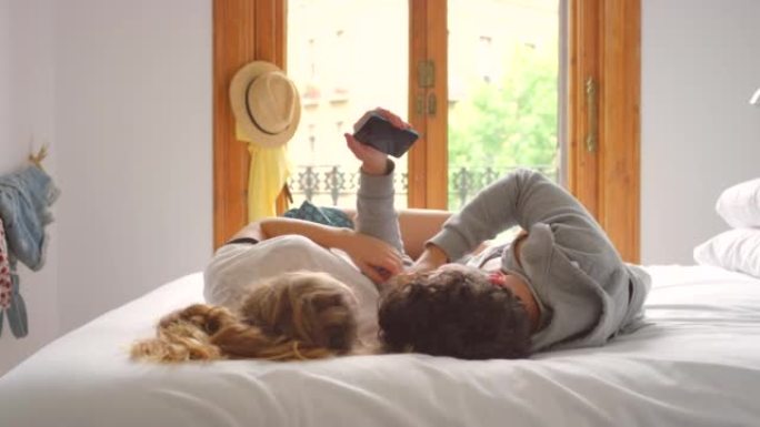 一对年轻夫妇在床上放松时使用智能手机的4k视频片段