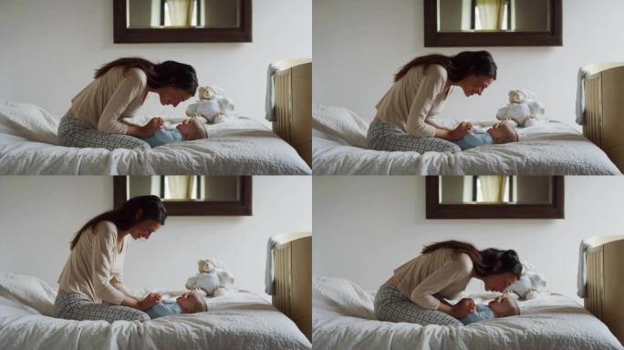 母亲在床上与新生婴儿玩耍的真实镜头