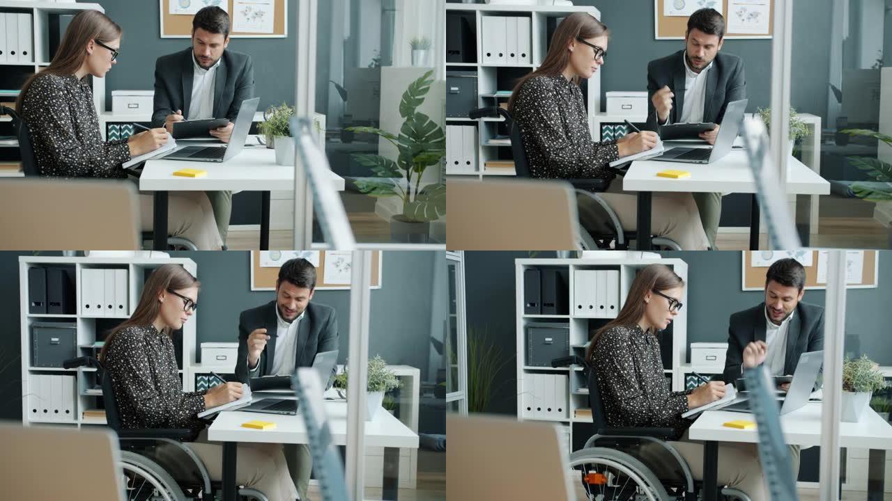 开朗的商人与坐在轮椅上的残疾同事一起在办公室工作