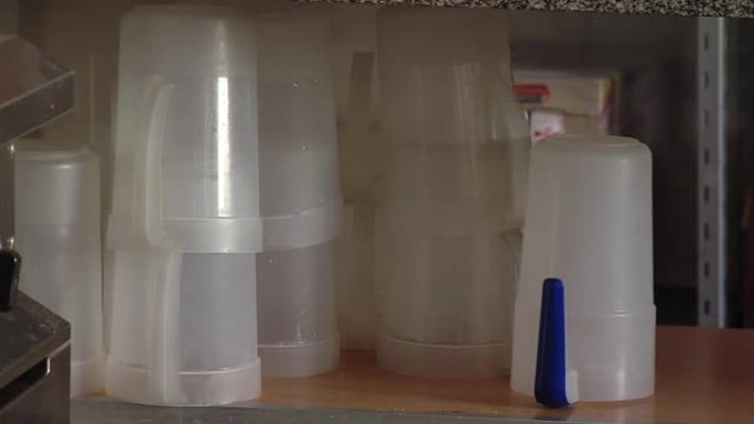 在学校食堂的厨房内堆放塑料杯和瓶子。特写。