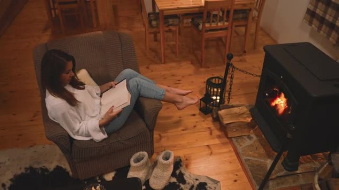 女人在家里壁炉旁的扶手椅上放松时看书