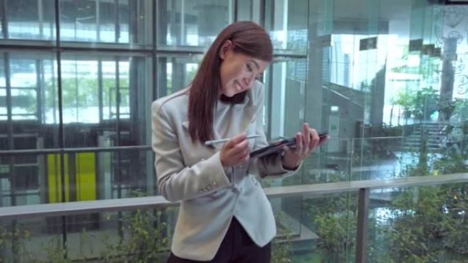 一个非常忙碌的女商人在使用平板电脑的同时在电话上聊天。