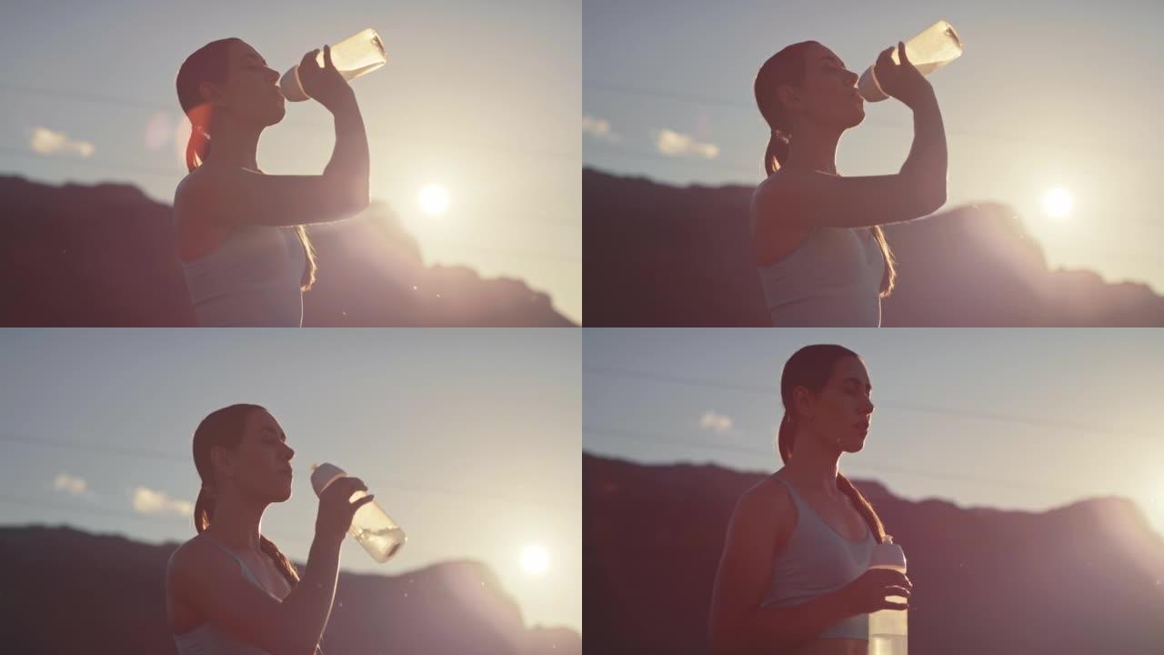 4k视频片段，一名年轻女子在日落时分在乡下跑步后喝水