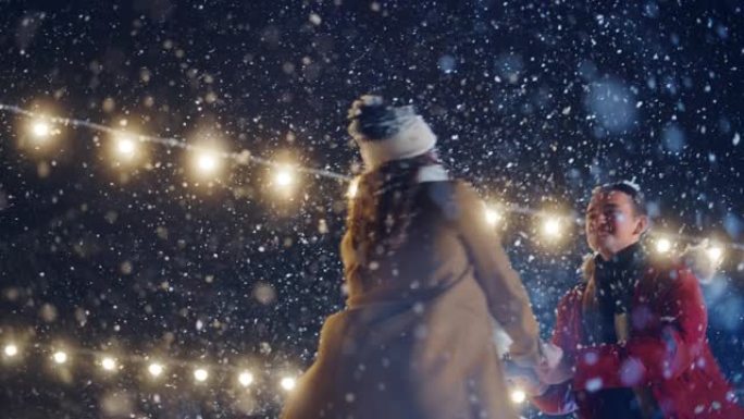 浪漫的冬天下雪的夜晚: 滑冰夫妇在溜冰场上玩得开心，旋转和跳舞。户外双人滑冰。温柔的年轻人，恋爱中的