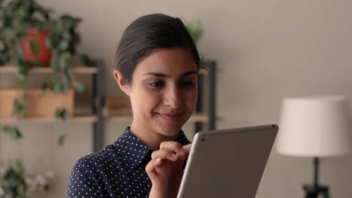 印度商务女士独自站在室内在平板电脑设备上工作