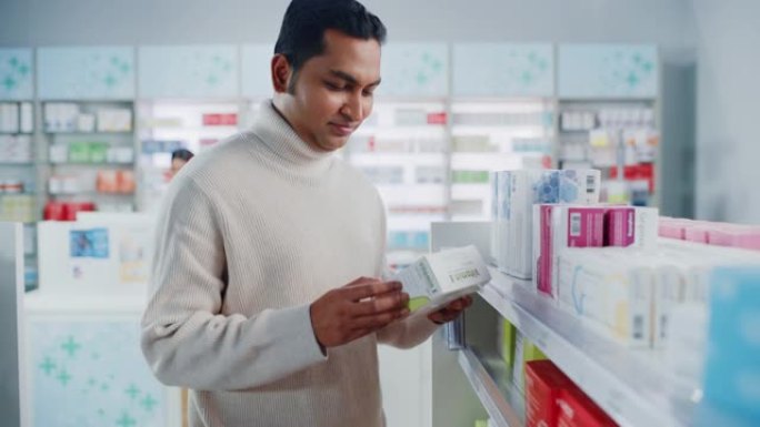 药房药店: 肖像英俊的印度男子选择买药浏览货架，成功找到他需要的东西，开心地微笑。现代制药商店保健产