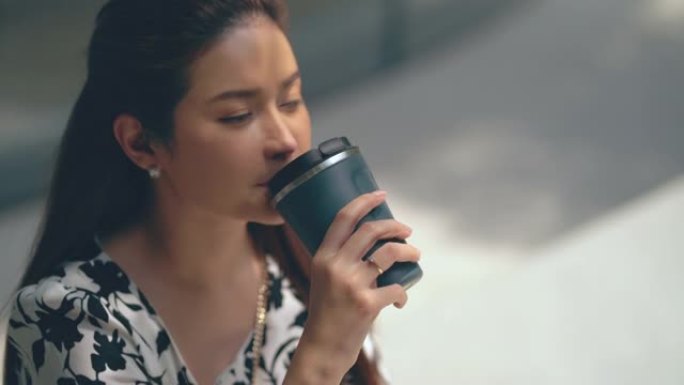 亚洲女人坐在户外咖啡馆微笑。