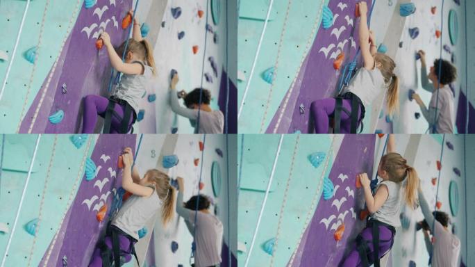 小女孩和年轻女子在健身房攀爬人造墙，专注于活动
