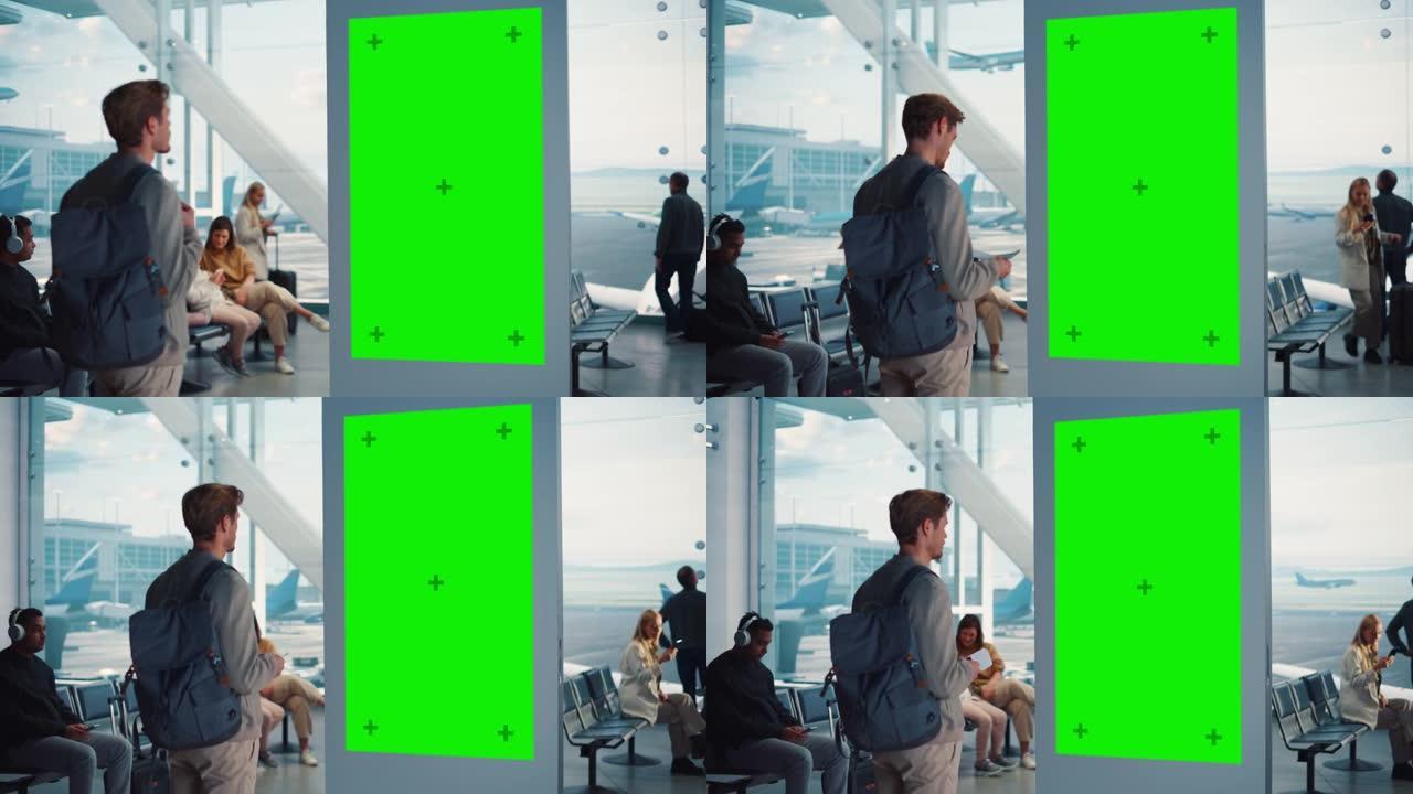 机场航站楼: 年轻人在绿色色度键屏幕上寻找他的飞弹到达出发信息显示。背景: 不同的人在航空枢纽的登机