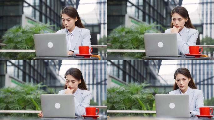 使用笔记本电脑在人行道咖啡馆工作的年轻亚洲妇女