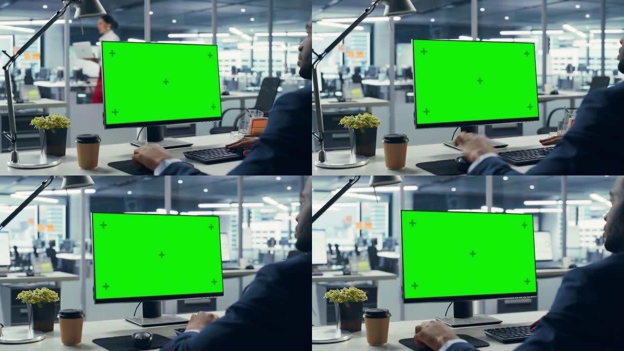 成功的黑人商人坐在办公桌前，在办公室里用绿屏笔记本电脑工作。使用色度键显示的非裔美国商人。肩弧射击