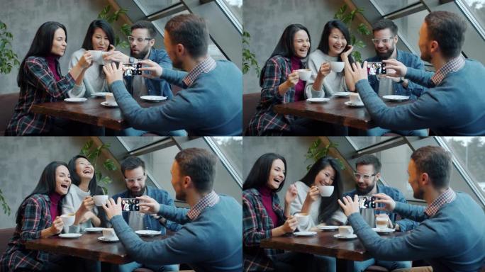 快乐的年轻人在咖啡馆用智能手机拍照时，碰着咖啡杯大笑