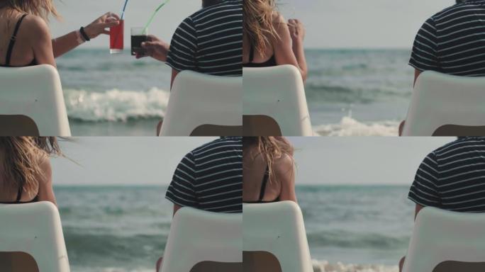 特写后视快乐成功的游客夫妇坐在海边的沙滩椅上触摸酒杯制作吐司