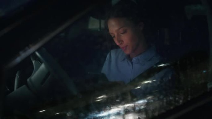 一名年轻的女商人晚上在外面下雨的时候在市中心驾驶一辆现代汽车。