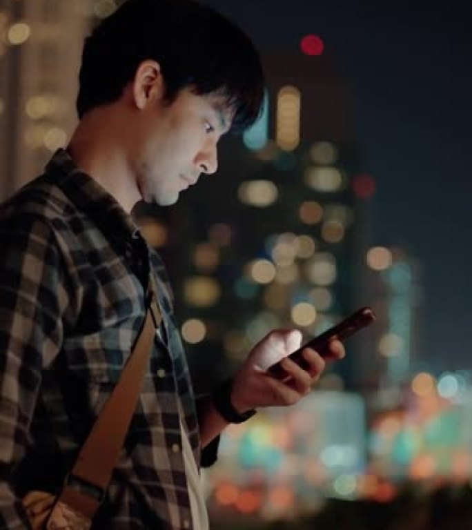 男人晚上在城市使用手机。