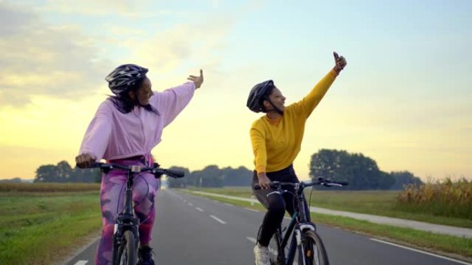 跟踪，手持拍摄两名成年女性在高速公路上骑行，在道路上行驶时自拍，慢动作