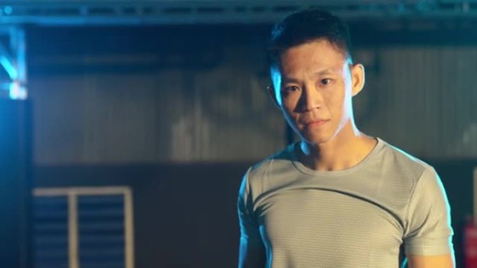 亚洲中国健身教练肖像弯曲肌肉看着相机，手臂交叉