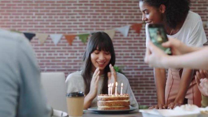 办公室生日，蛋糕派对和朋友庆祝创意工作者，吹蜡烛许愿，并在代理商处与食物一起唱歌。员工对甜点和鼓掌庆