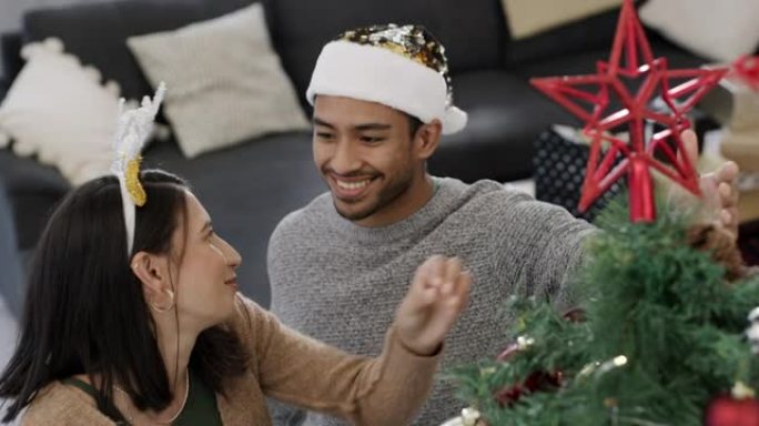 4k视频片段，一对年轻夫妇在家中与一颗星星一起完成圣诞树装饰