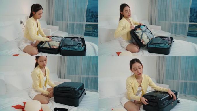 亚洲女人打包行李，在床上拉上拉链