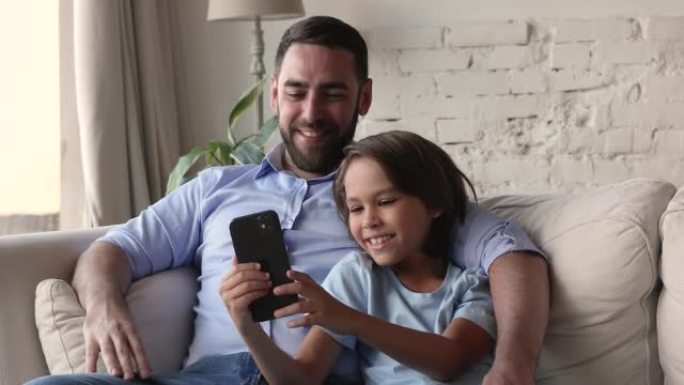 男孩和爸爸使用现代智能手机在互联网上度过时光