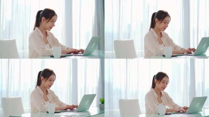 亚洲女商人使用技术笔记本电脑进行在线学习并在房间的办公桌上工作