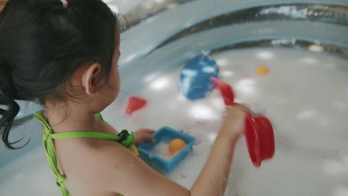 顽皮的女孩在充气游泳池的水上玩玩具和泡泡。