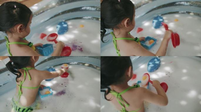 顽皮的女孩在充气游泳池的水上玩玩具和泡泡。