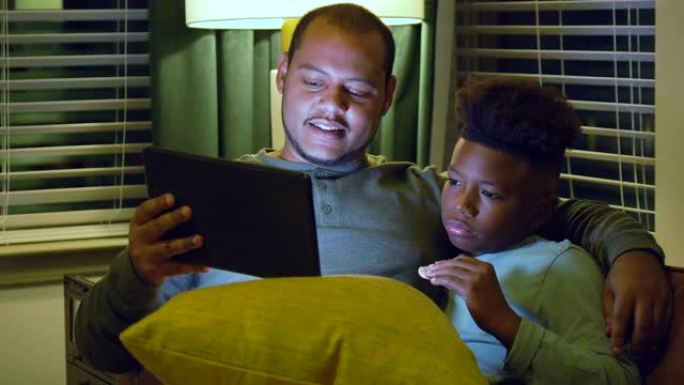 多种族的父亲和继子看着数字平板电脑