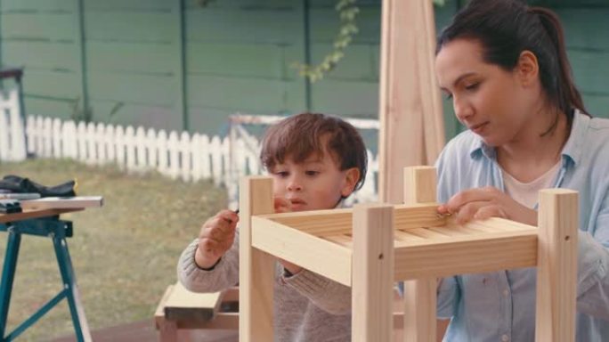 4k视频片段，一名年轻女子与她可爱的儿子在家中从事木制项目