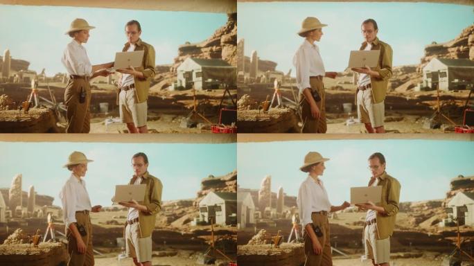 考古挖掘现场: 两位伟大的考古学家站在挖掘现场的帐篷工作中，使用笔记本电脑检查新发现的古代文明建筑遗