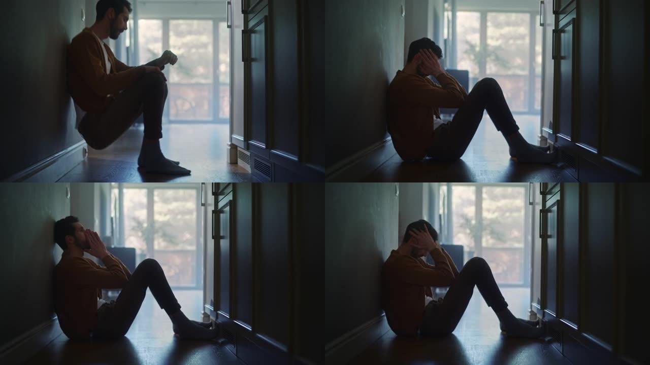 悲伤的中年男子滑下公寓的墙壁，用手遮住脸。家庭中抑郁、疾病、悲剧、死亡的气氛。戏剧性的坏消息电影慢动