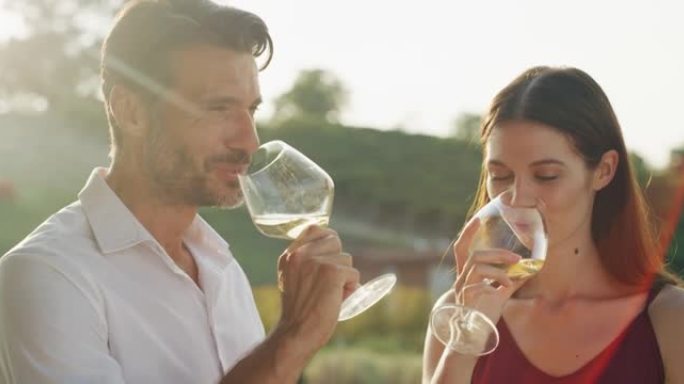 真实的爱情幸福夫妇的镜头是享受浪漫的约会，用白酒杯欢呼，庆祝他们的周年纪念日和风景优美的葡萄园背景下