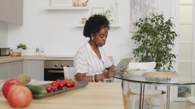 餐桌上有数字平板电脑的非洲裔美国妇女