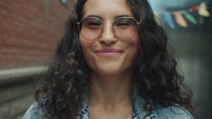 可爱的混血女人戴眼镜的特写肖像在城市街道外面笑着