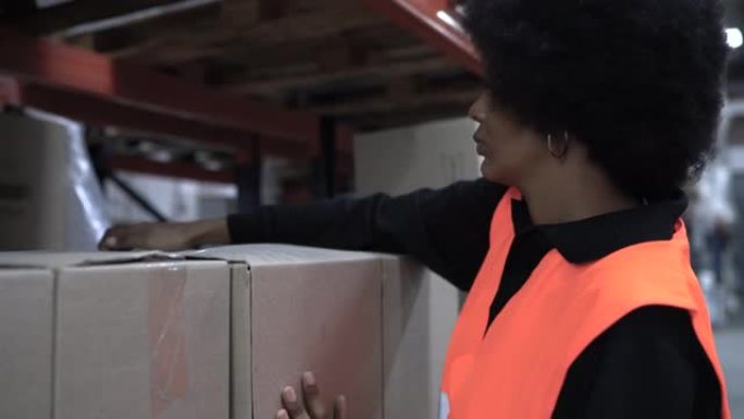 在大型分销仓库中工作的妇女整理箱子