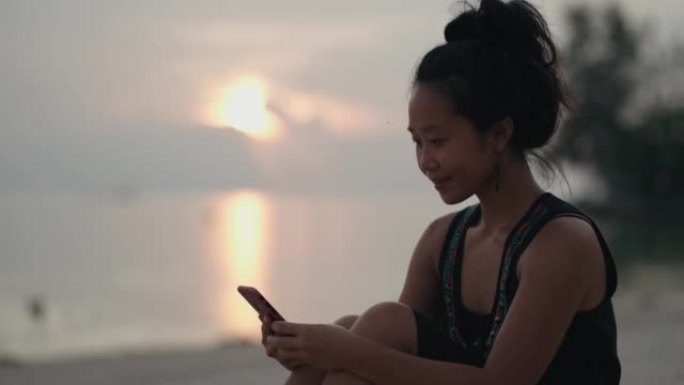 日落时在海滩上使用电话的女人