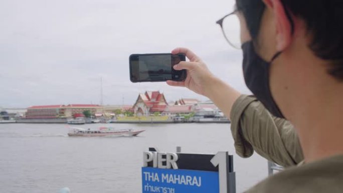 亚洲成年女性在泰国当地旅行时使用智能手机拍照。迷人的女性使用手机摄影，并在当地旅行时发送给她的社交媒