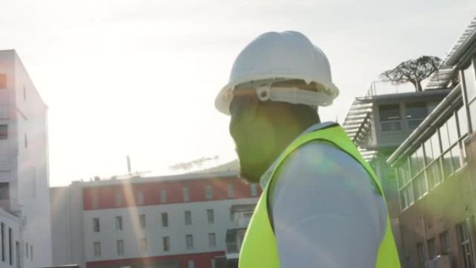 年轻的建筑经理戴着头盔环顾工作现场的建筑物。自信的行业专业检查发展。非洲承包商检查该地块。