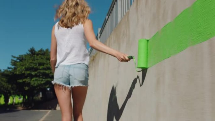 年轻女性艺术家用绿色油漆绘画墙壁行走在城市街道上独立女性享受城市涂鸦艺术表达4k
