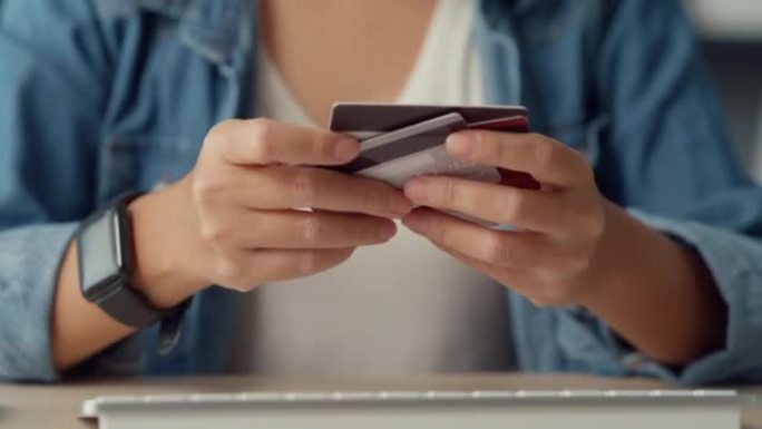 年轻的亚洲女士使用电脑订购网上购物产品，并在客厅内部用信用卡支付账单。呆在家里，自我检疫活动，冠状病