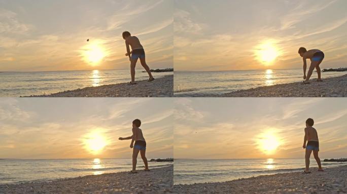SLO MO小男孩在日落时在海滩上向大海扔石头